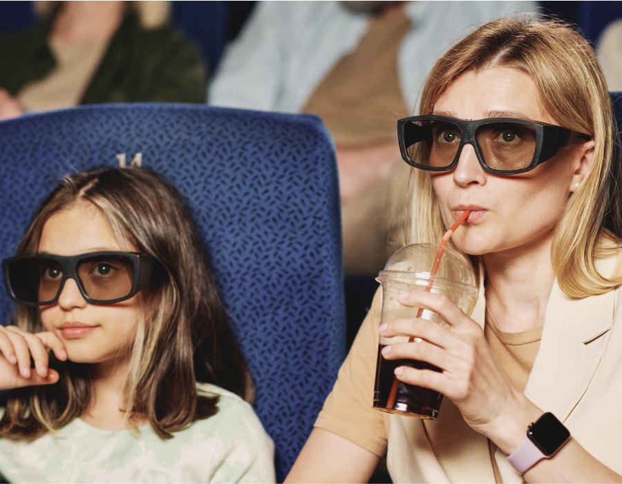 A woman and a girl wearing modern 3d glasses at the movie theater