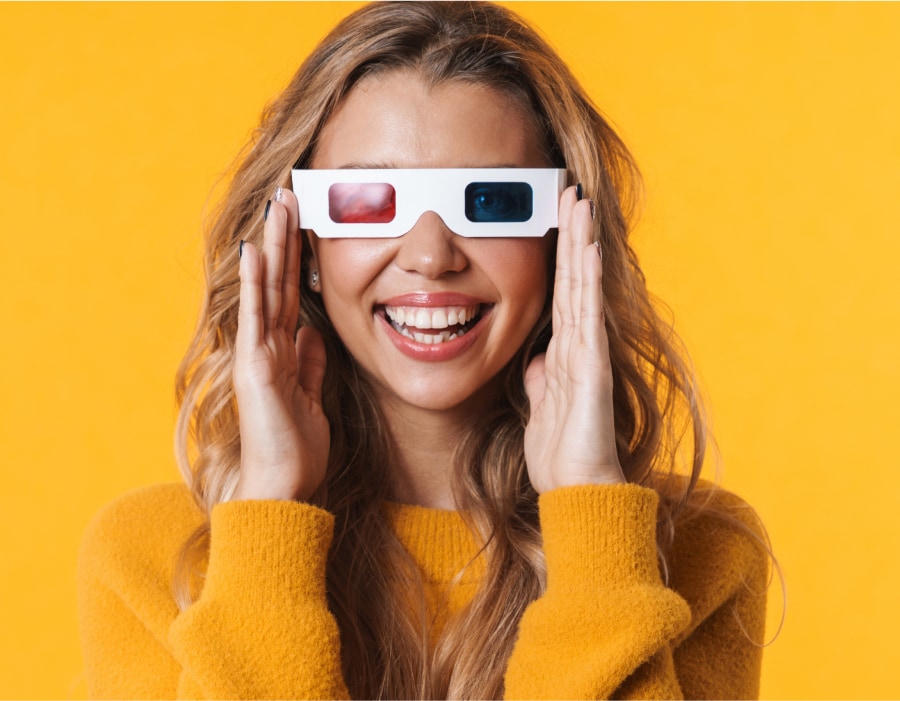 A woman in front of a yellow background wearing old-style 3d glasses