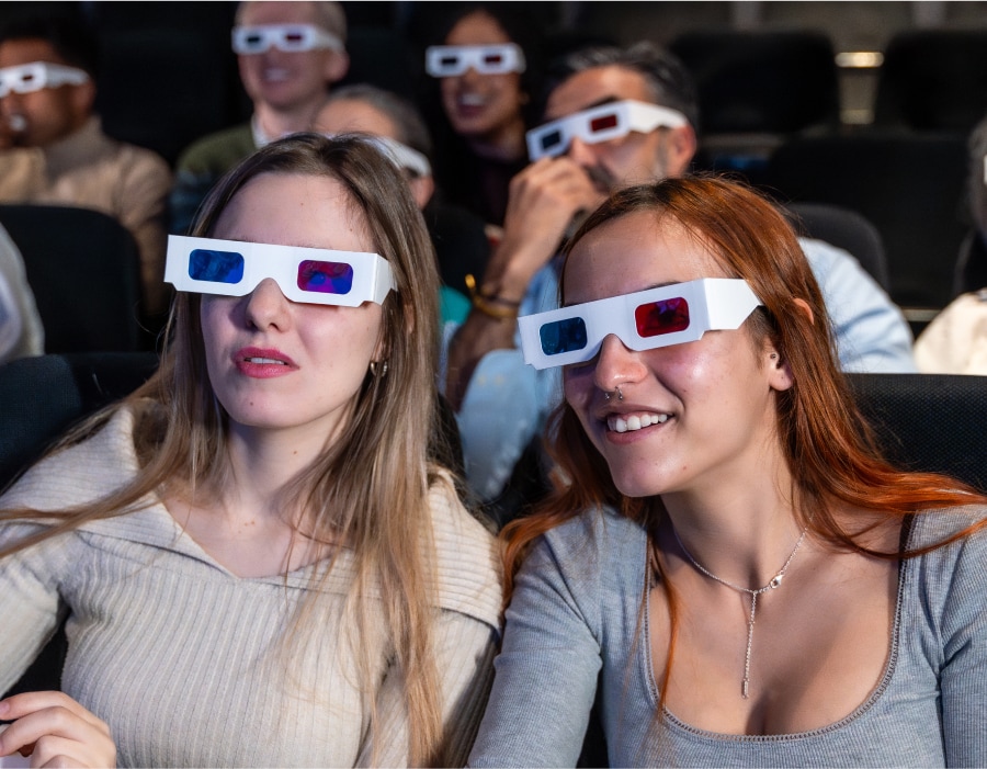 Two women at a movie theater wearing 3d glasses