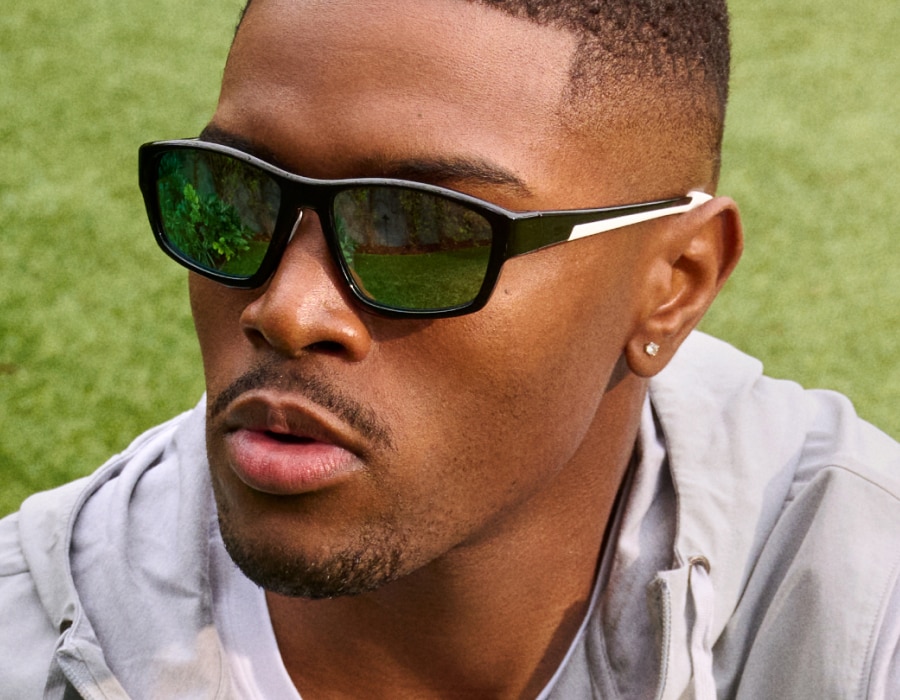 A man with short hair in a field wearing sunglasses