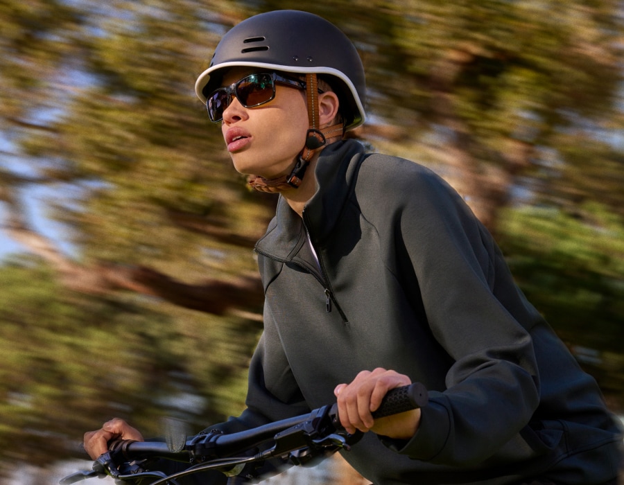 A man riding a bike in front of trees wearing a helmet and sunglasses