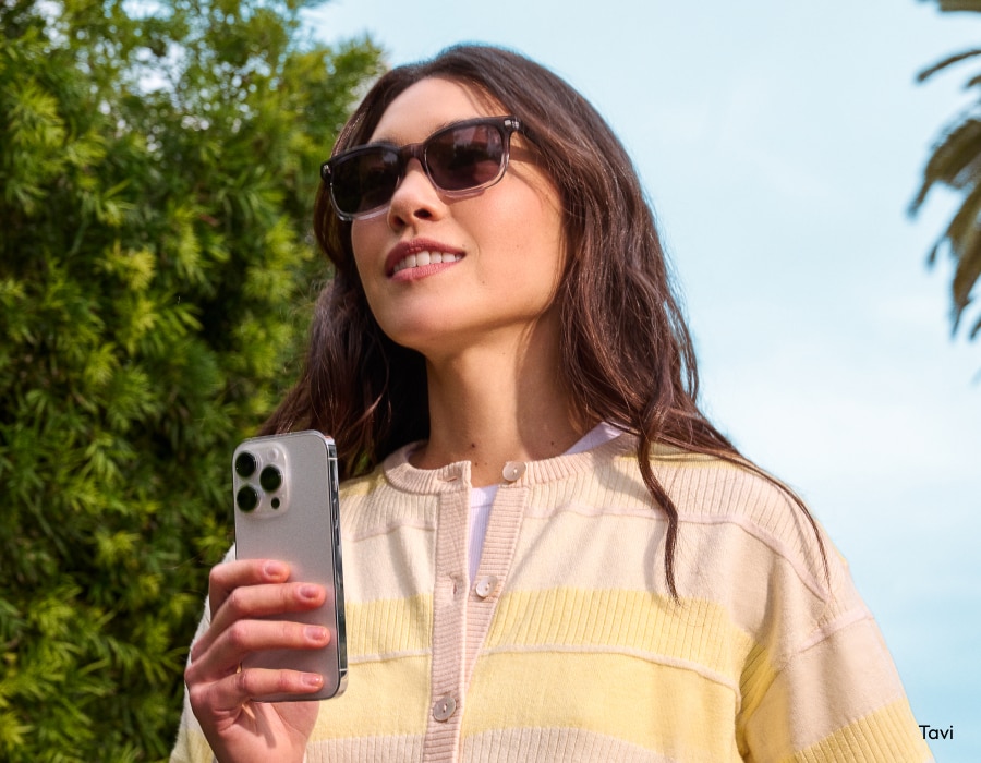A woman outside wearing sunglasses and holding a phone