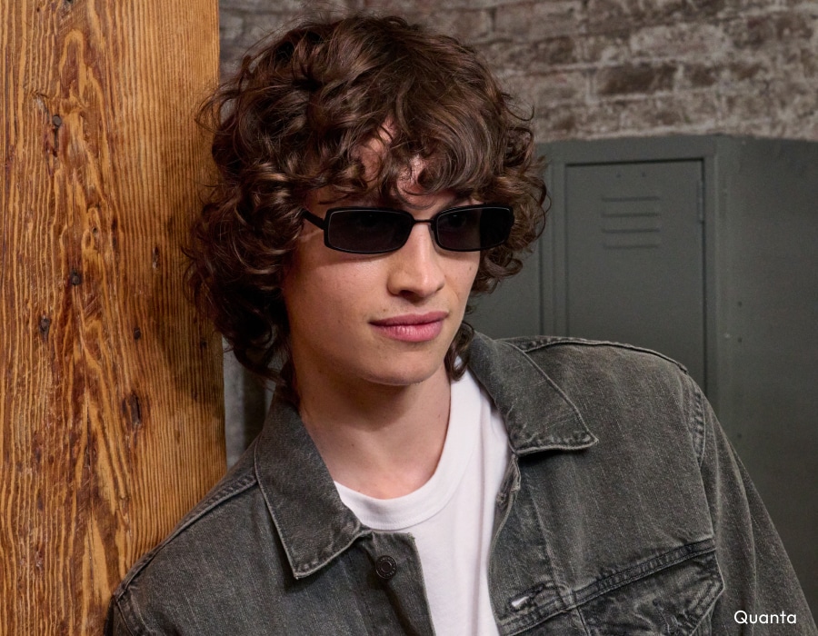 A man with curly brown hair wearing sunglasses with rectangular frames