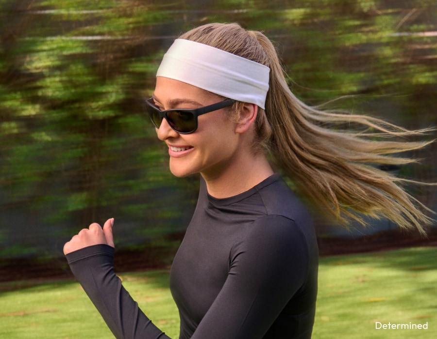 A woman running outside wearing sunglasses