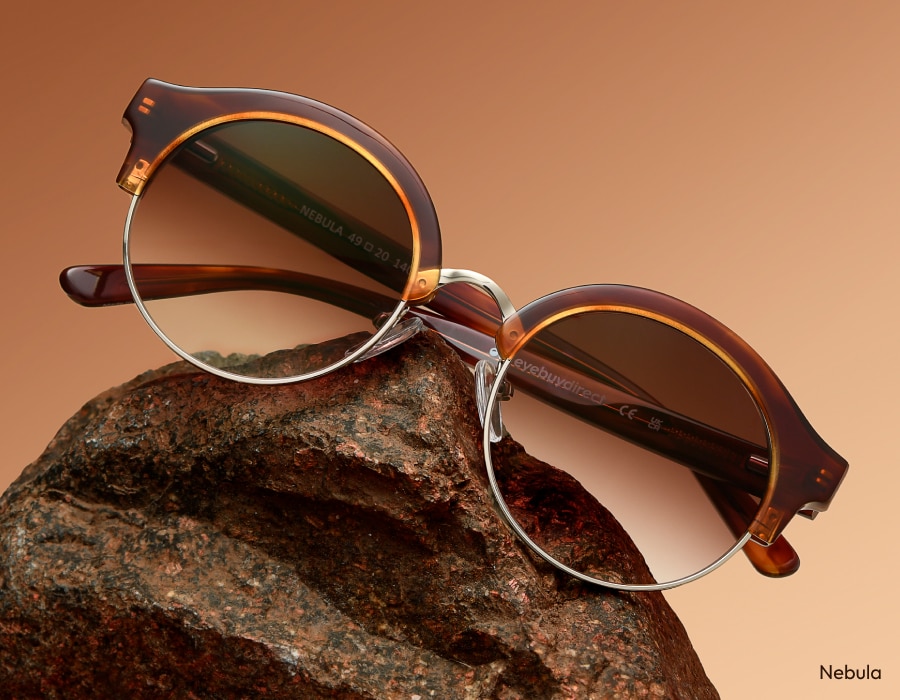 A flatlay of a pair of clubmaster-style sunglasses with gradient lenses