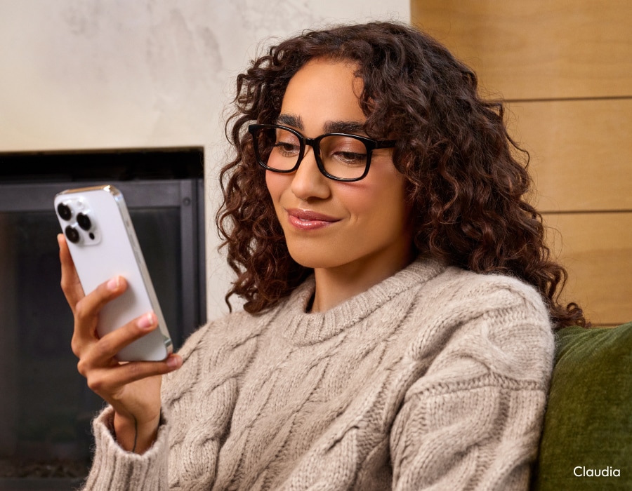A woman wearing glasses with anti-fatigue lenses looking at her phone