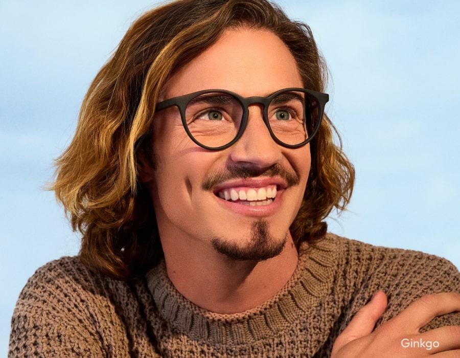 A man smiling wearing large eyeglasses a matte texture