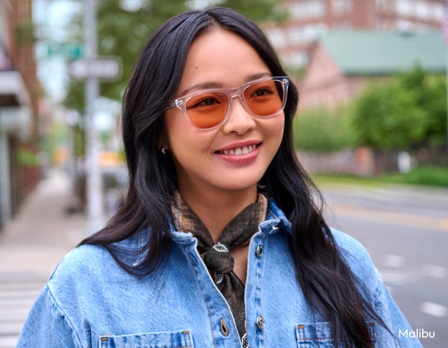 A woman wearing a denim jacket and sunglasses with orange lenses