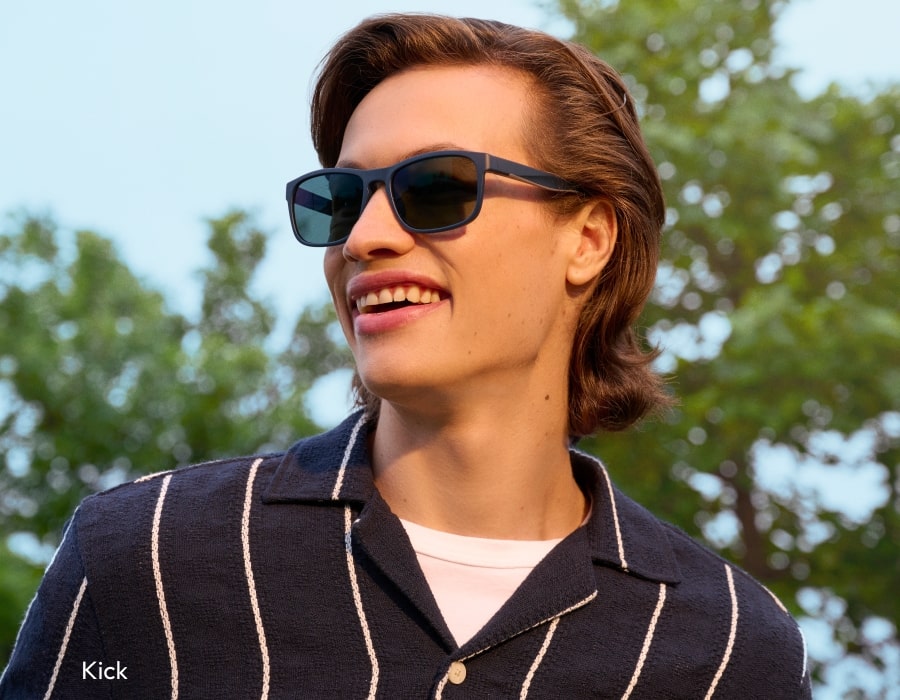 A man wearing a striped shirt and large sunglasses with matte blue frames