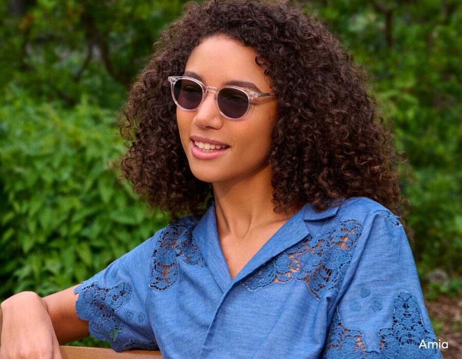 A woman wearing a blue shirt and small sunglasses with translucent frames