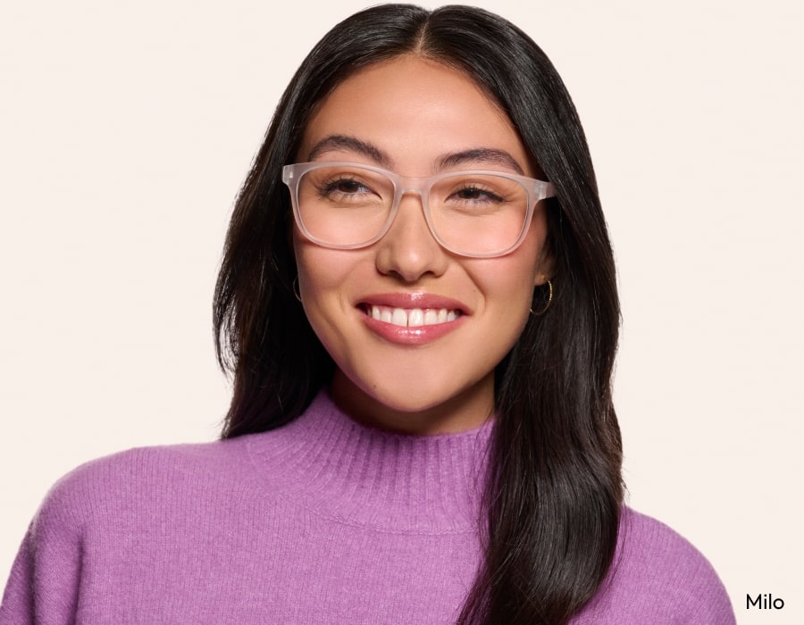 A woman wearing a pink sweater smiling and wearing eyeglasses with translucent frames