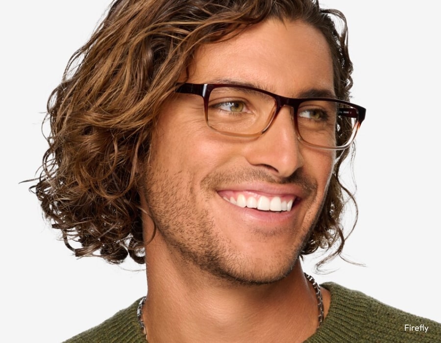 A man smiling and wearing eyeglasses with brown frames