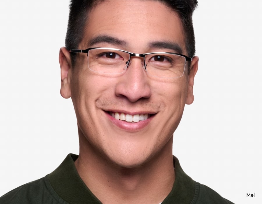 A man smiling and wearing semi-rimless eyeglasses with narrow lenses