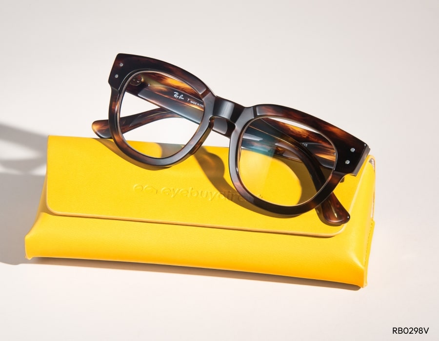 A pair of eyeglasses on a yellow glasses case with thick tortoiseshell frames