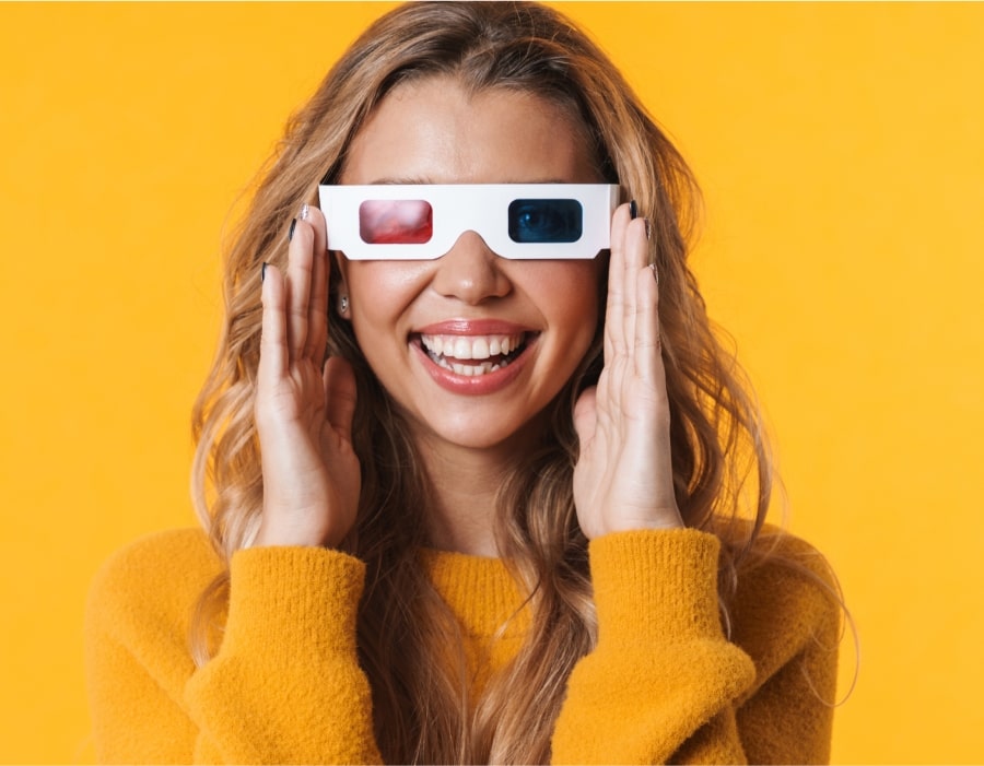 A woman in front of a yellow background wearing old-style 3d glasses