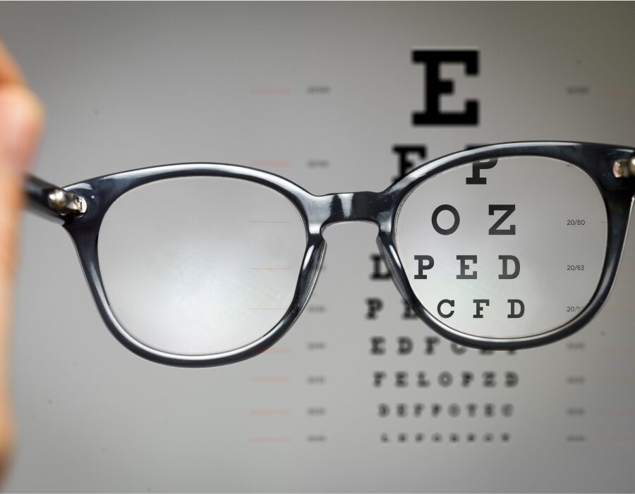 A snellen eye chart behind a pair of eyeglasses