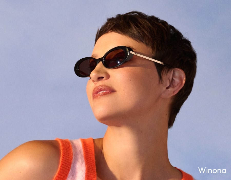 A woman with short hair wearing oval sunglasses