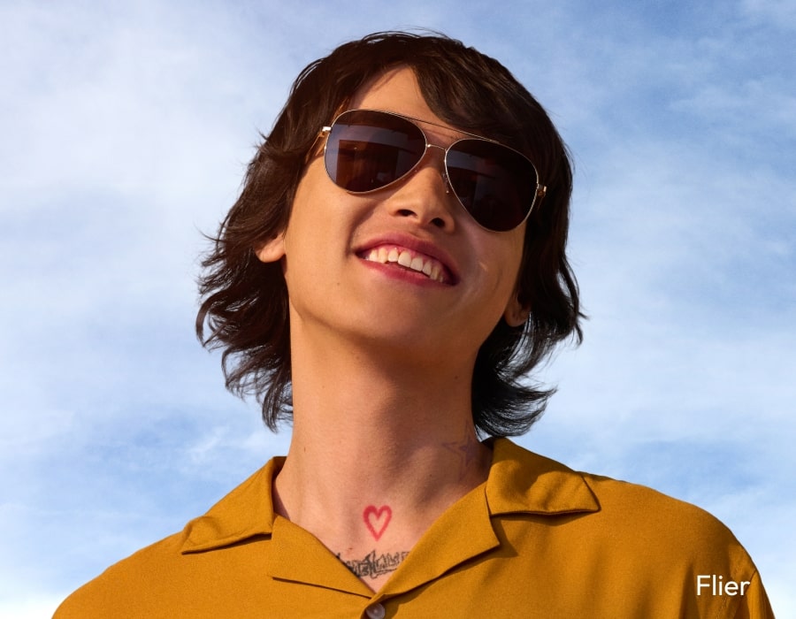 A person in front of a blue sky wearing aviator sunglasses