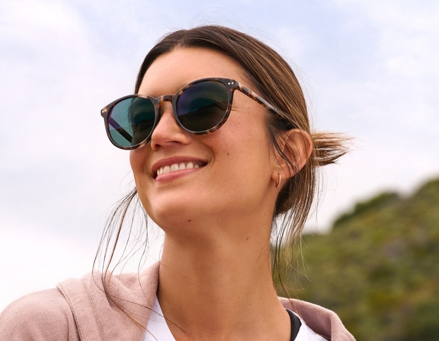 A woman outside smiling and wearing sunglasses
