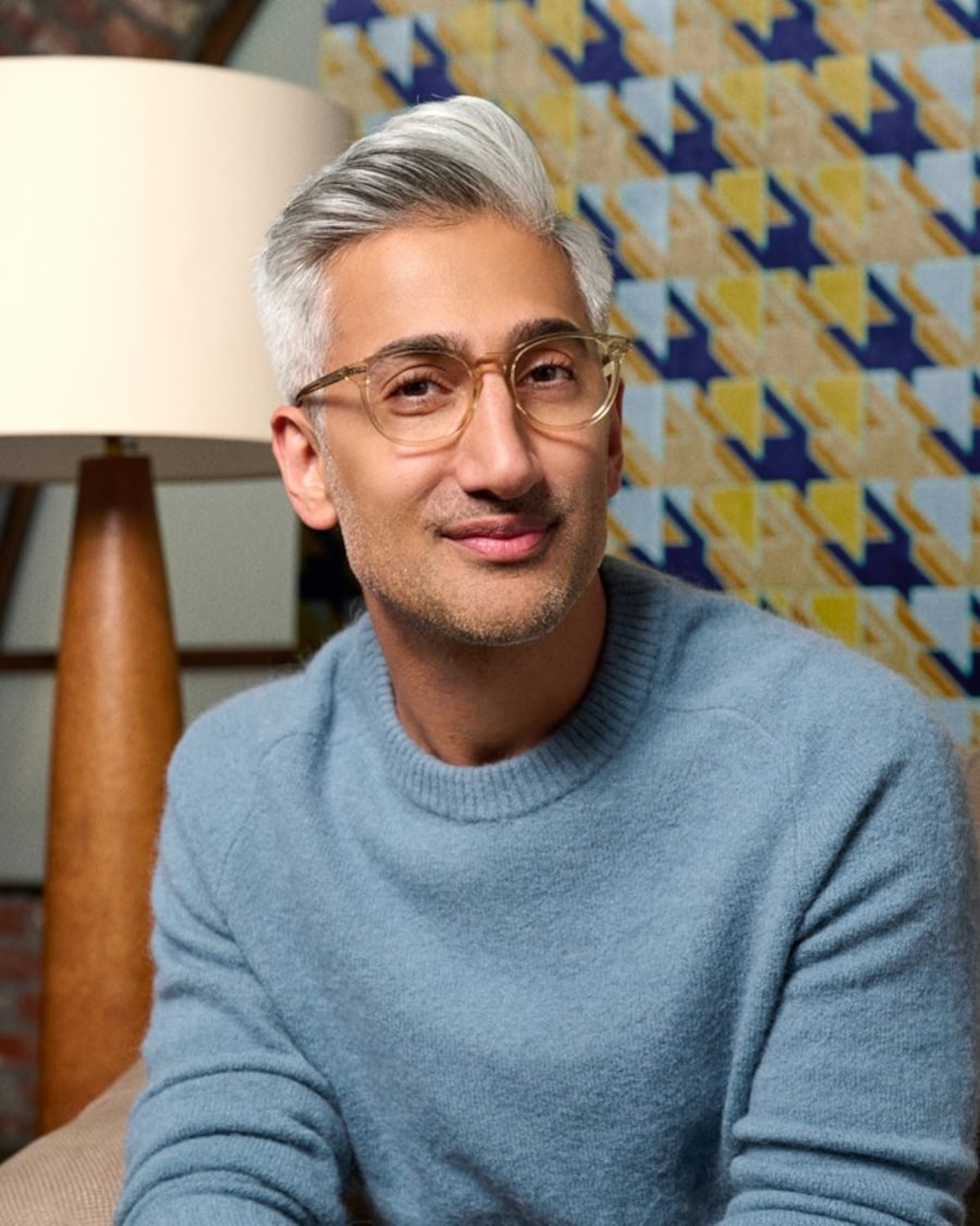 Tan France wearing a blue sweater and eyeglasses with translucent frames