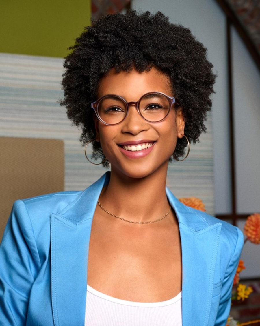 A woman wearing a light blue jacket and round eyeglasses