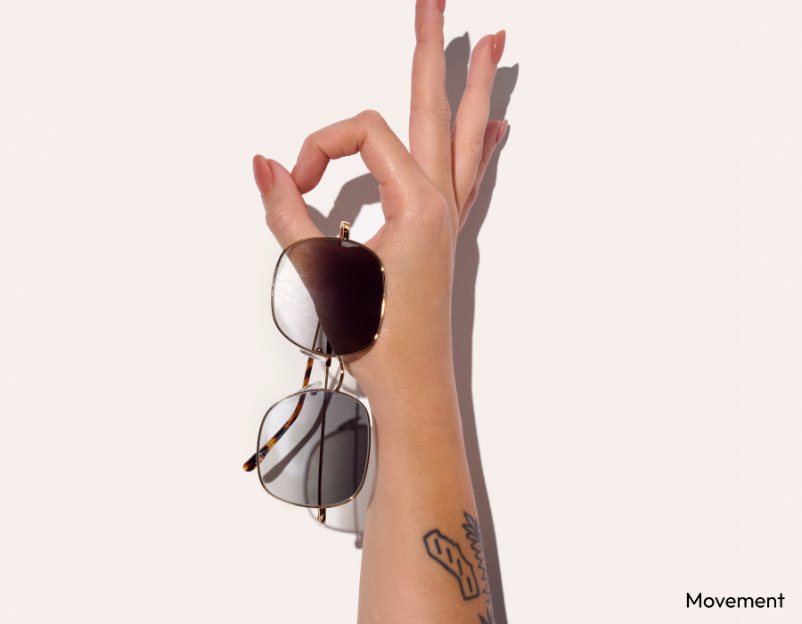 A hand doing an 'ok' gesture holding a pair of sunglasses