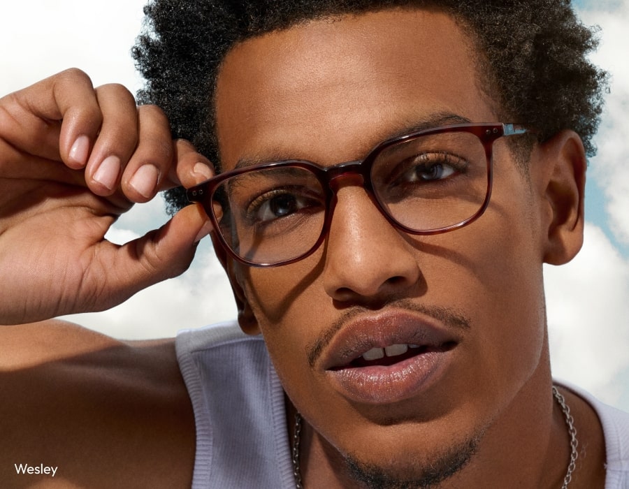 A man looking at the camera wearing tortoiseshell eyeglasses with anti-reflective lenses