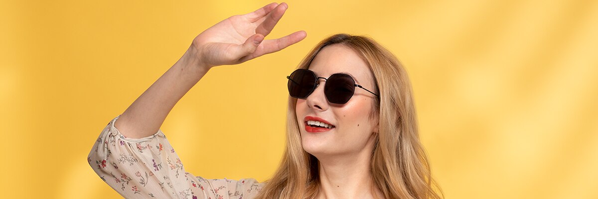 A woman wearing sunglasses in front of a yellow background