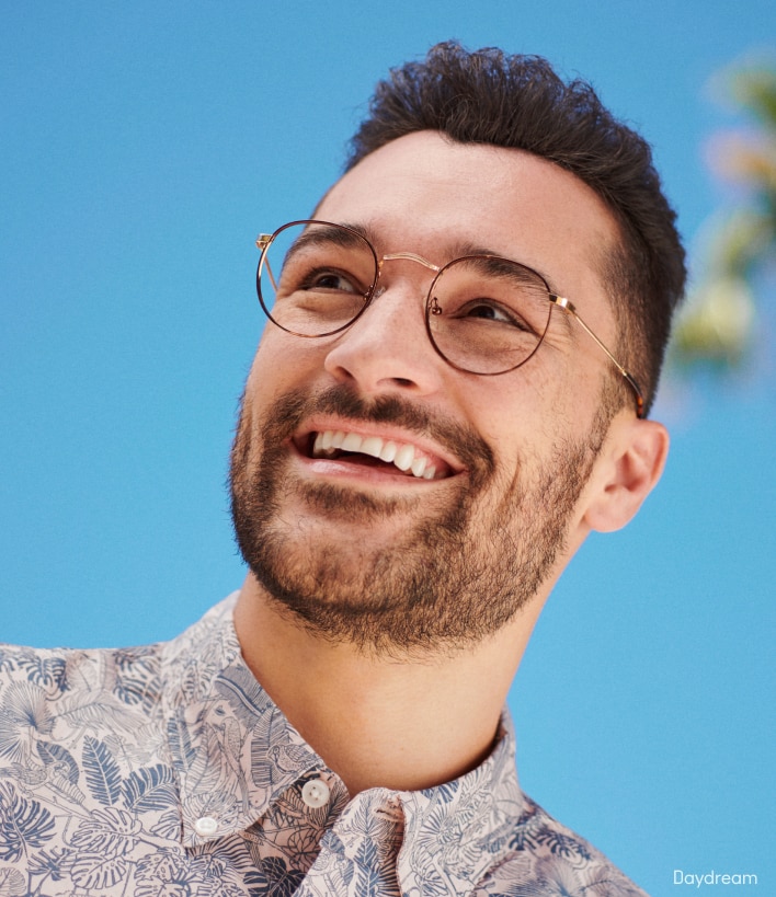 A man with a beard smiling wearing reading glasses