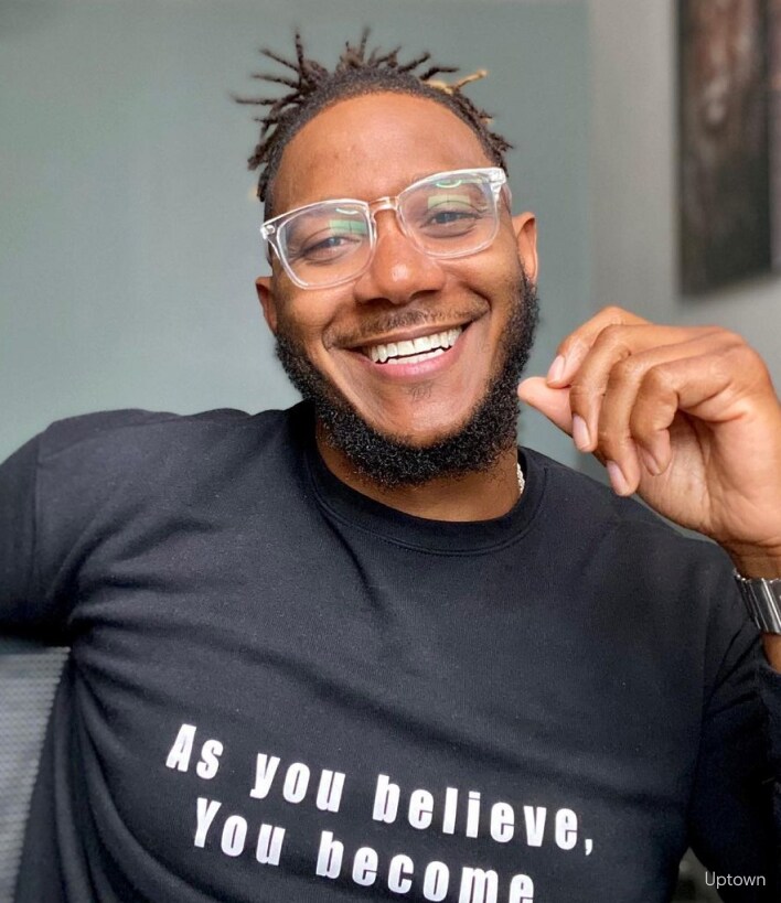 A man smiling wearing blue light glasses