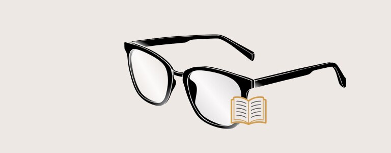 Person with a bald head and gray beard is wearing glasses and smiling with teeth, looking at the camera while holding a book.  