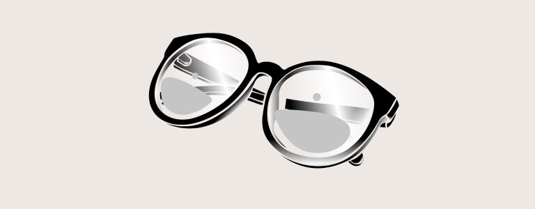 Une personne aux cheveux brun clair portant une chemise bleue carreautée et des lunettes sourit légèrement en regardant la caméra vers la gauche.