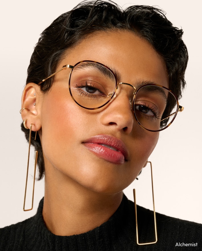 A woman wearing gold-colored eyeglasses with round  tortoiseshell patterned lenses
