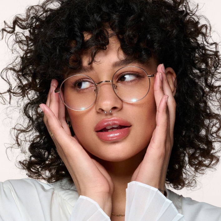 A woman with curly hair wearing eyeglasses with round frames