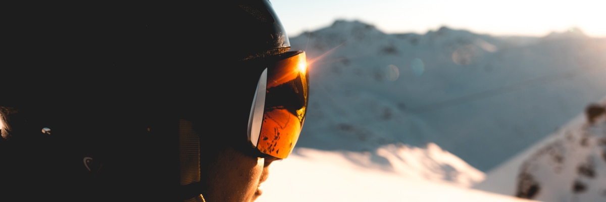 A person wearing skiing goggles looking at a snowy mountain